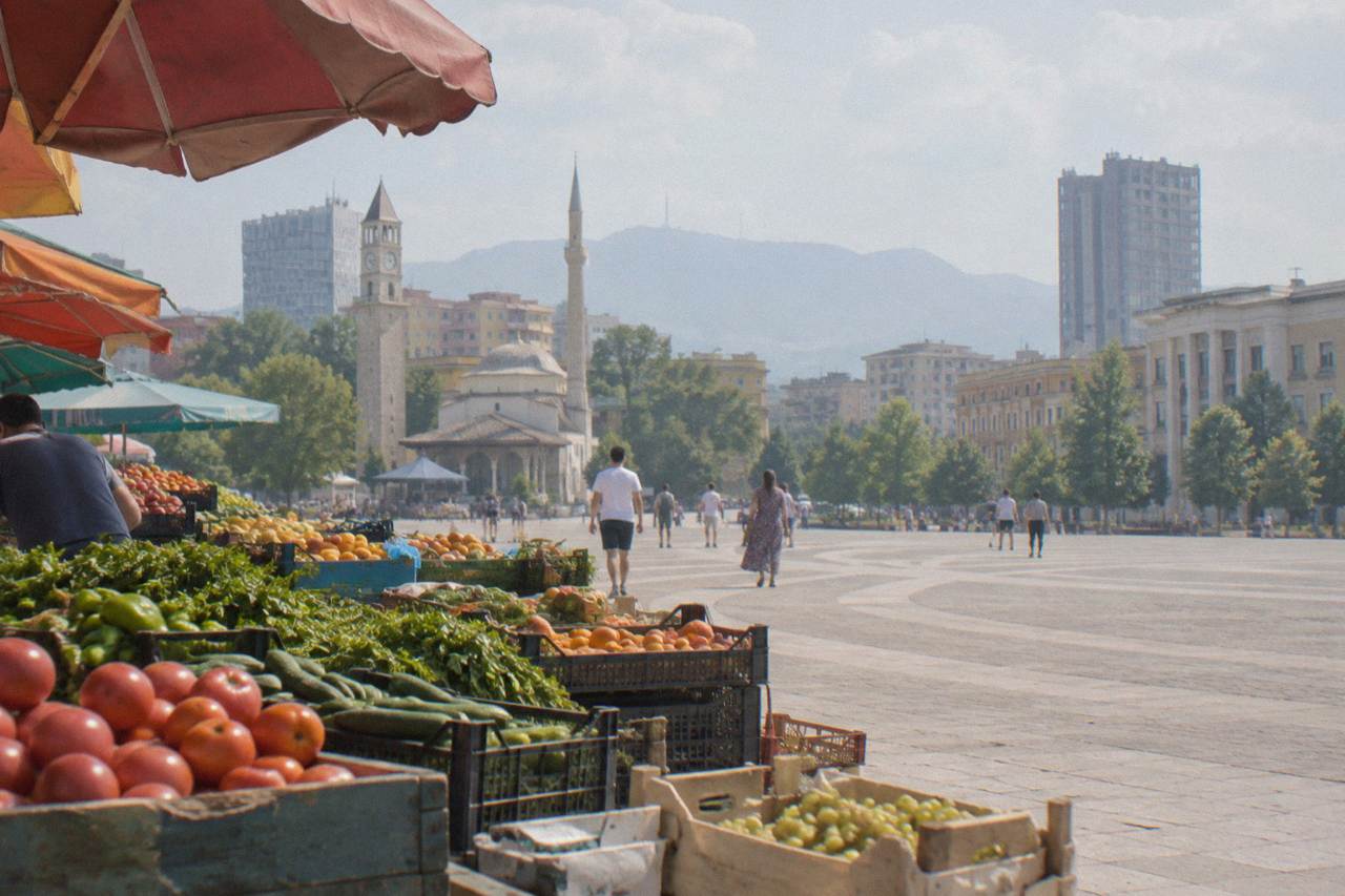 Fruit and vegetable stalls under the coloured awnings of a market street in Tirana