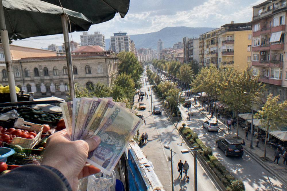 Albanian lek banknotes held out at a market stall counter
