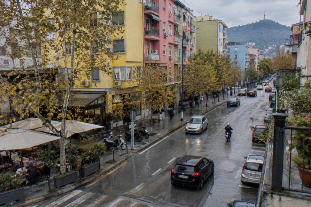 Brightly painted apartment blocks in different colours seen from a Tirana street corner