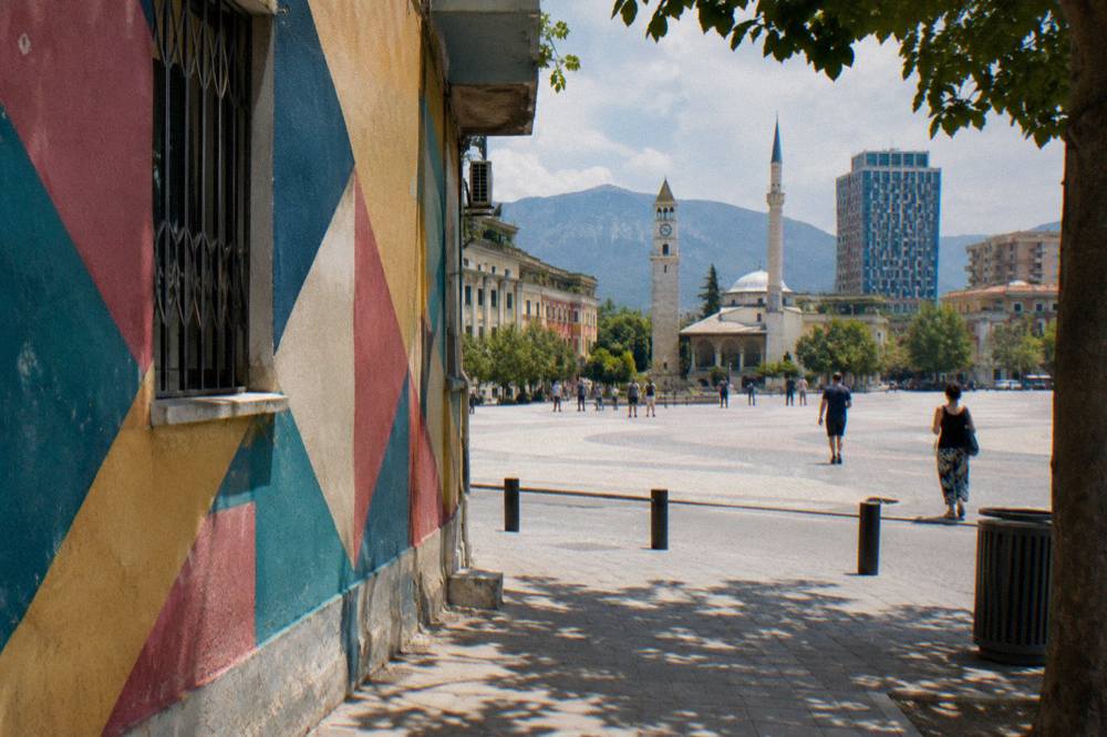 A painted wall with bold geometric colour patterns on a residential street in Tirana