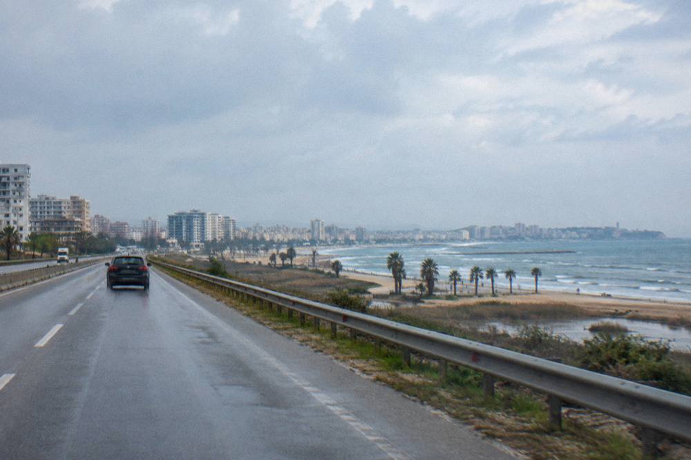A car driving on a motorway across a flat coastal plain toward the sea