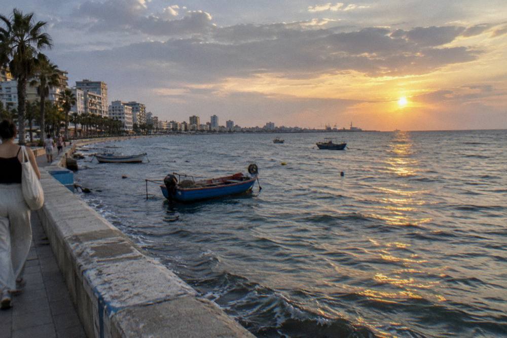 Sunset over the Adriatic Sea seen from the promenade at Durres with fishing boats near the shore