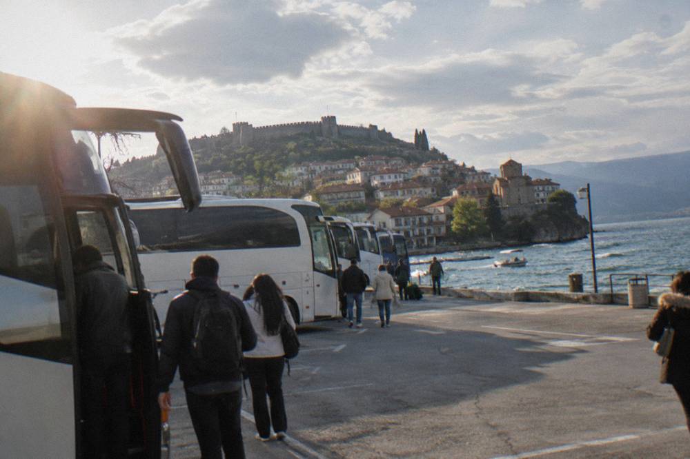 A row of intercity buses parked at a terminal with passengers boarding