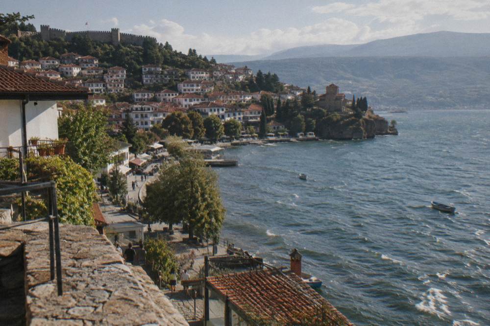 A small lakeside town with a promenade and wooded hills behind calm water