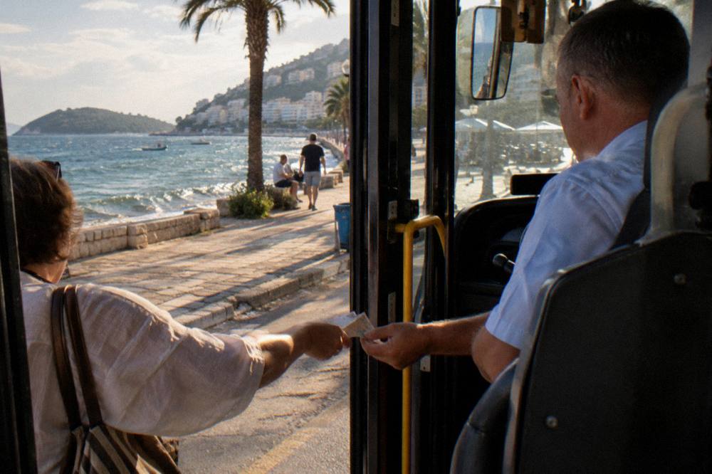 A passenger handing banknotes to a bus driver at a vehicle door