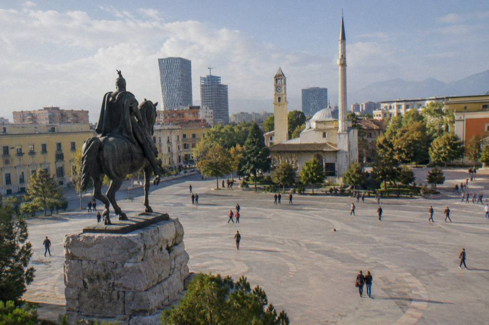 Skanderbeg Square in Tirana with the equestrian statue and mosque minaret under a blue sky