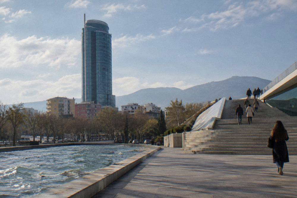 A stepped modern building with people walking up its sloped exterior stairs