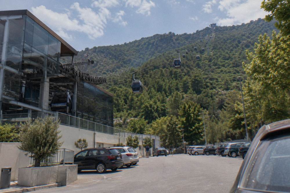 Cable car cabins travelling on a long line above green forested slopes