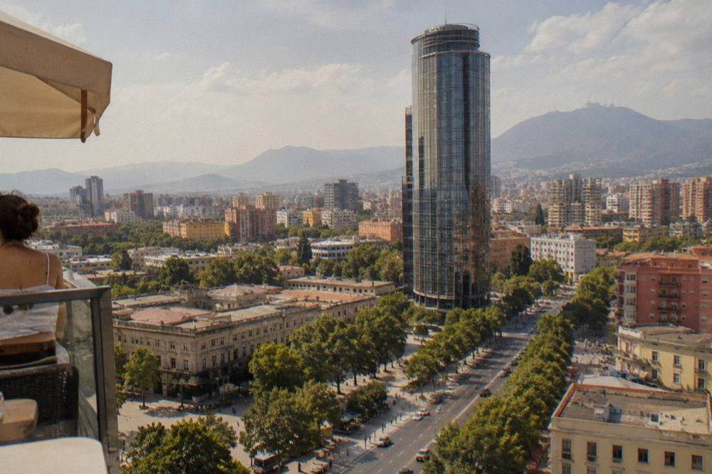 Hazy summer morning light over a Balkan city skyline with distant mountains