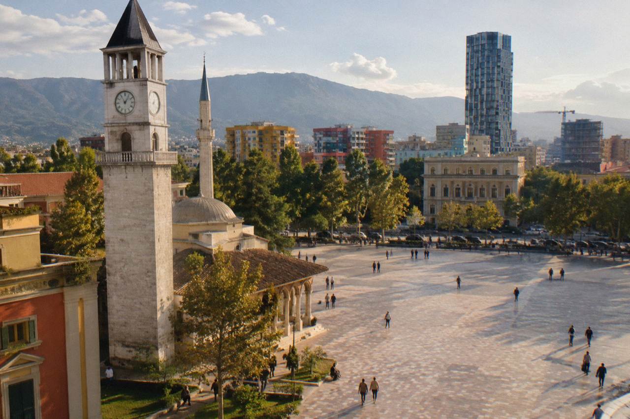 Skanderbeg Square in Tirana under a clear sky with the clock tower and mosque in the background