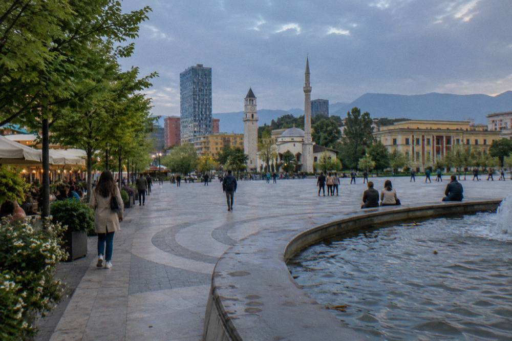 A tree-lined boulevard in Tirana in late spring sunshine with cafes along the pavement