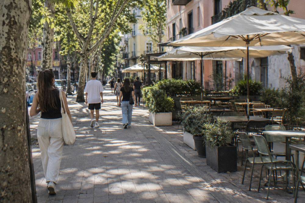People walking along a shaded street in Blloku during a warm afternoon