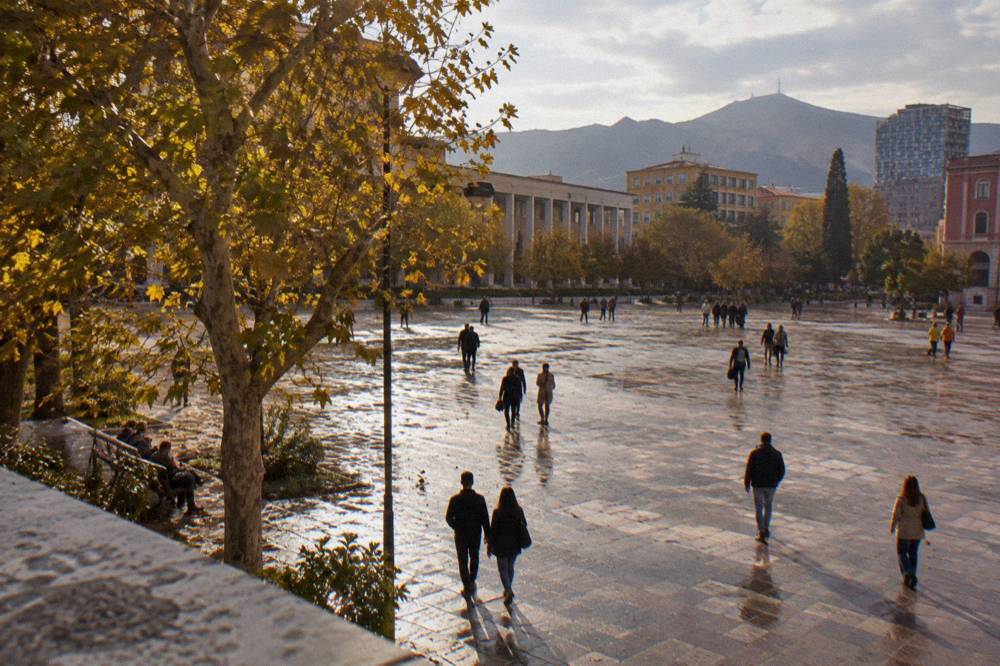 Visitors walking across Skanderbeg Square on a warm autumn afternoon