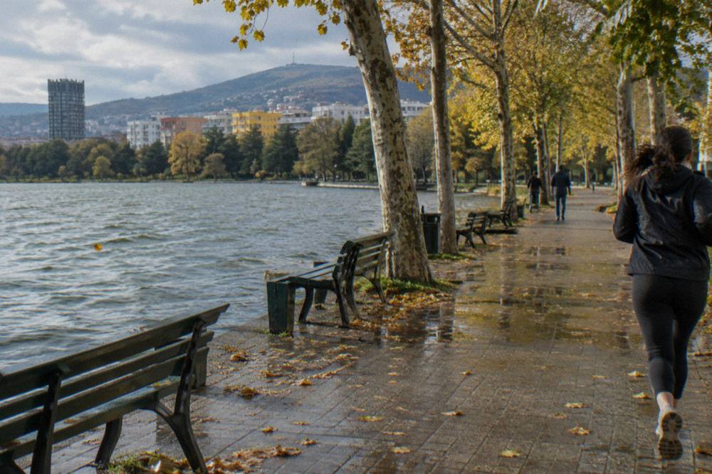 The Tirana Artificial Lake and Grand Park under a mild autumn sky with the hills behind