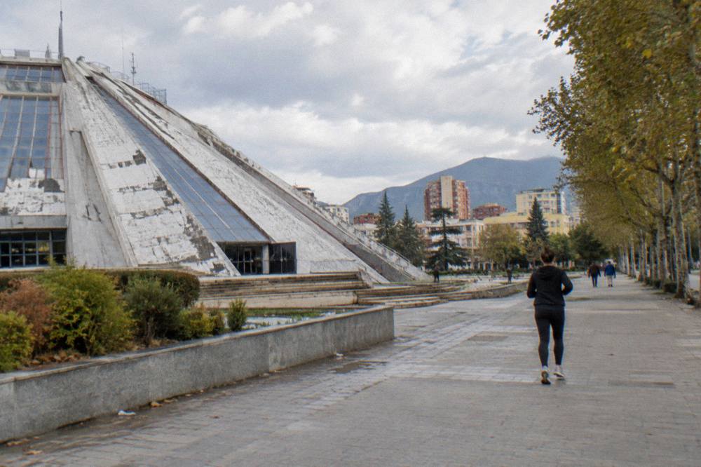 The Pyramid of Tirana and city rooftops under a partly cloudy sky