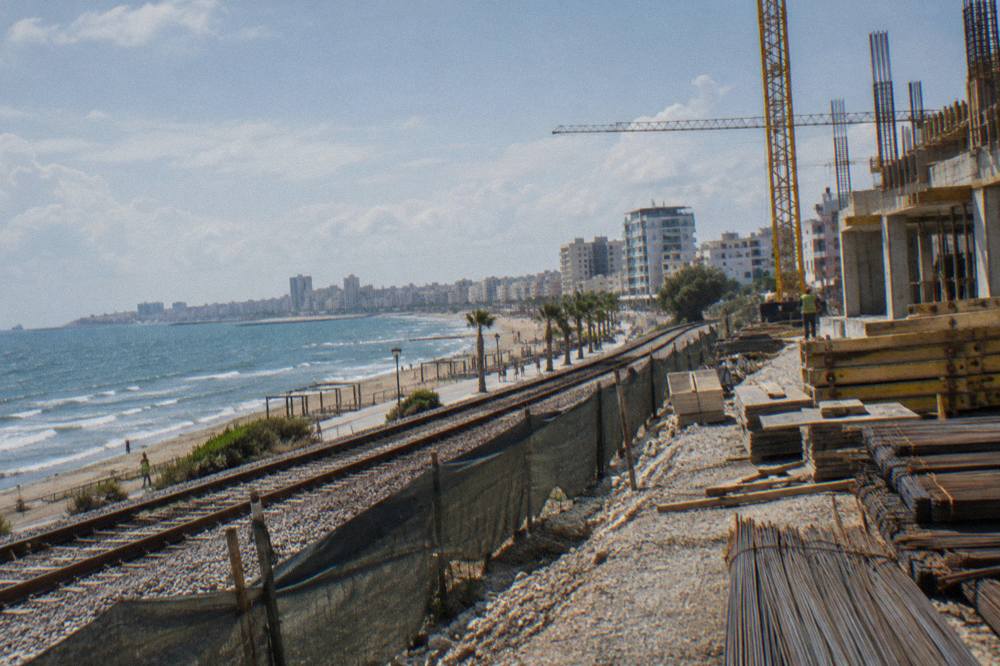 A construction site along a railway embankment with cranes and building materials