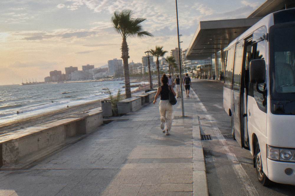 An airport shuttle bus parked outside a terminal building at dusk