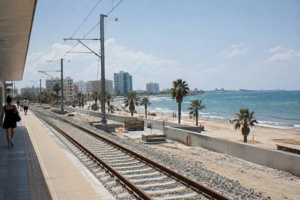 Freshly laid railway tracks with catenary poles under construction beside a station platform