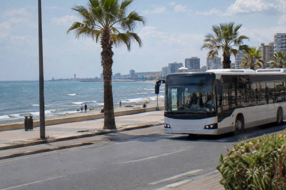 A modern bus travelling along a coastal road with the sea on the horizon