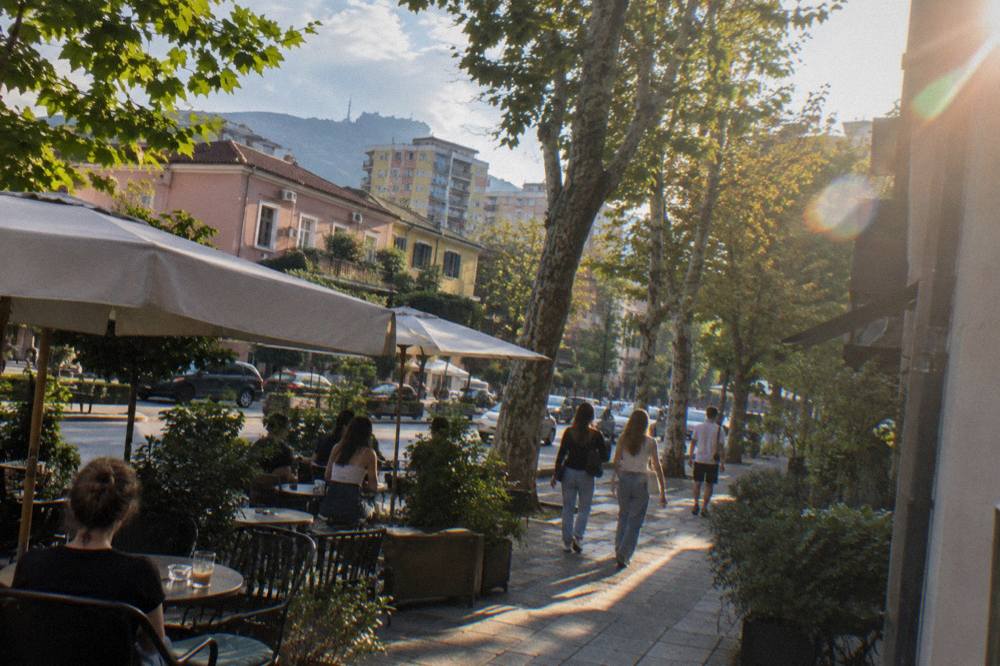 Cafe tables and trees along a street in the Blloku quarter of Tirana