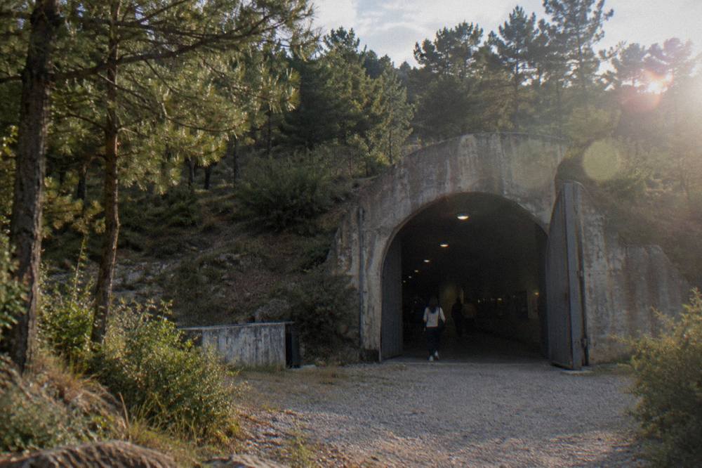 A dark concrete tunnel inside a bunker museum, lit by sparse overhead lights