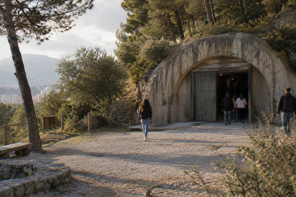 Visitors reading exhibit panels in a long underground corridor of a bunker museum