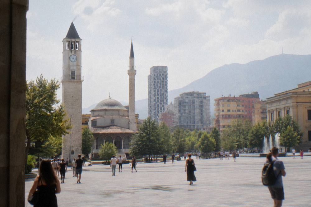 The wide pedestrian expanse of Skanderbeg Square with the mosque minaret and clock tower at its edge