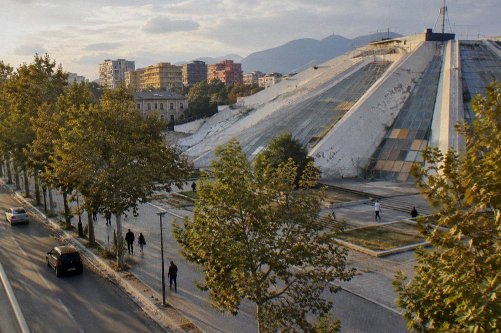The stepped glass-and-concrete slopes of the Pyramid of Tirana seen from the boulevard
