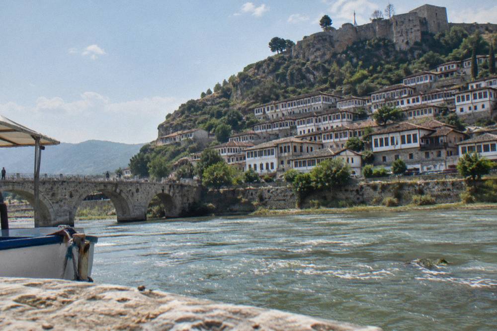 White Ottoman houses stacked on the hillside inside Berat castle quarter under a clear sky