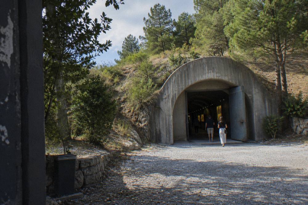 A restored bunker tunnel entrance at Bunk'Art lit with display lighting inside the hillside