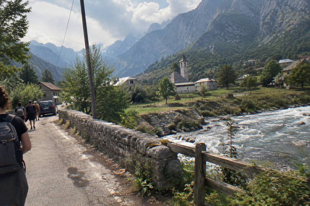A winding mountain road with stone peaks above it on the way to Theth
