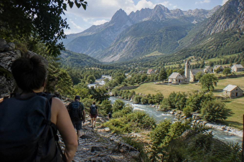 Hikers descending a rocky trail toward the green Valbona valley