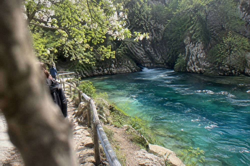 A turquoise karst spring pool between canyon walls at the Blue Eye of Theth