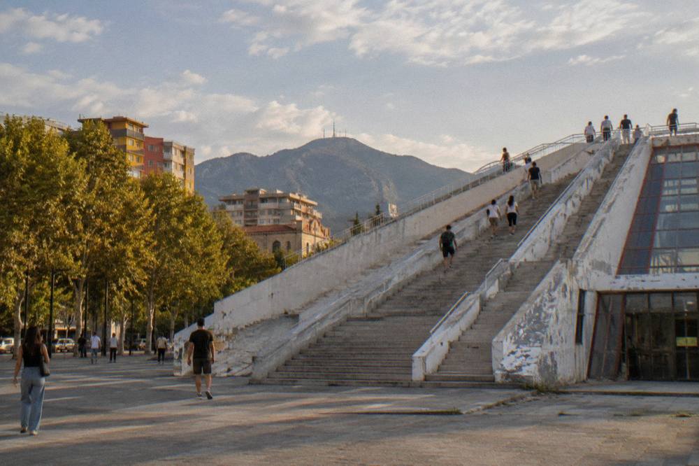 The restored Pyramid of Tirana with people climbing its exterior steps toward the viewing platform