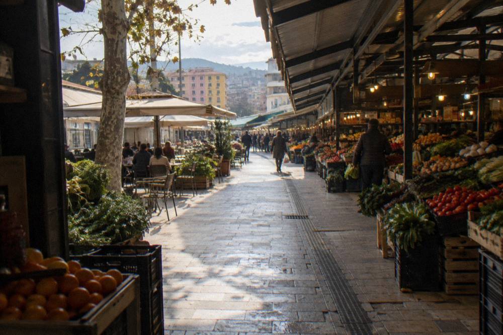 Covered market alley with produce stalls and warm lights at the New Bazaar in Tirana
