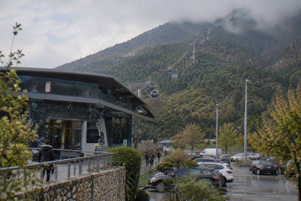 Cable car cabins travelling up a green mountain slope through low clouds