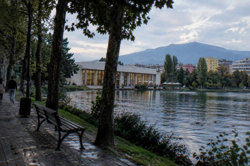 Rain-lit castle walls above a small Albanian town seen from a wet road