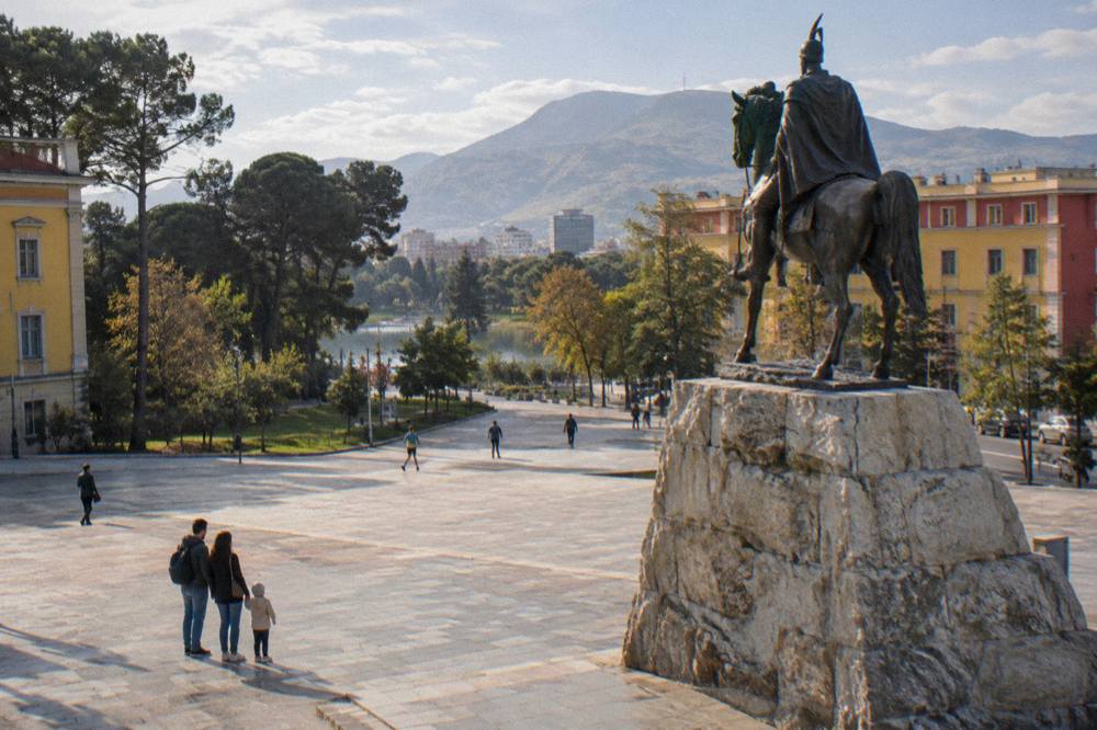 A family with a small child looking at the equestrian statue and coloured buildings around a large city square