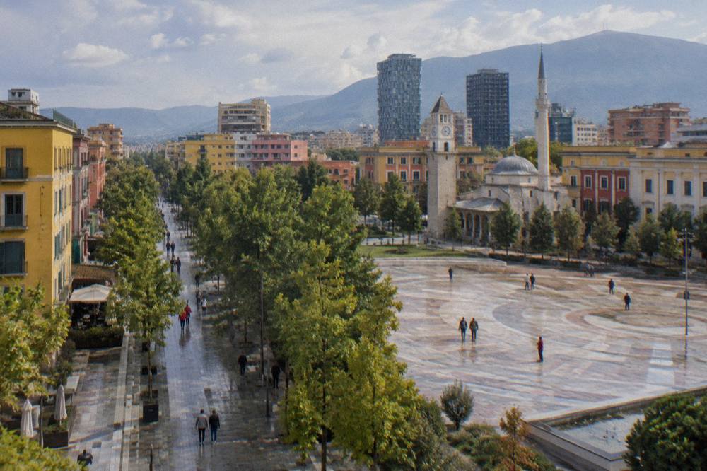 A pedestrian boulevard in central Tirana lined with trees and colourful buildings