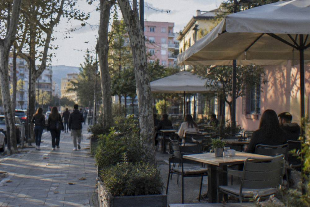 Cafe tables and trees on an evening street in the Blloku quarter of Tirana