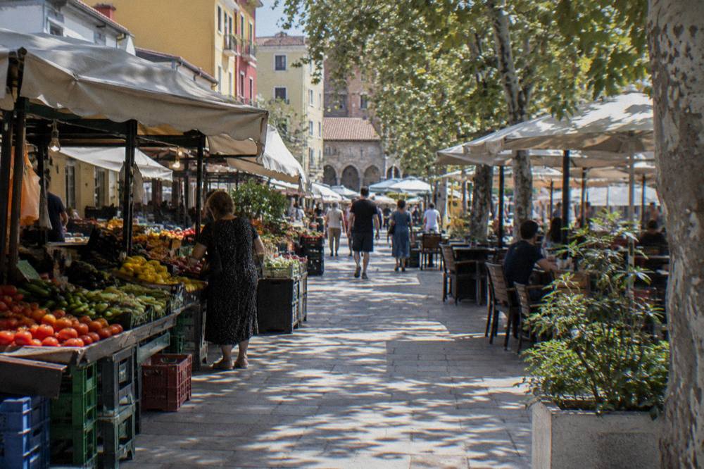 A shaded pedestrian lane in the New Bazaar of Tirana with market awnings and cafe tables
