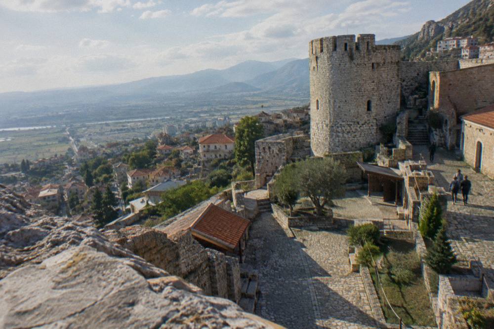 The stone walls and watchtower of Kruja castle above a hilltop town in Albania
