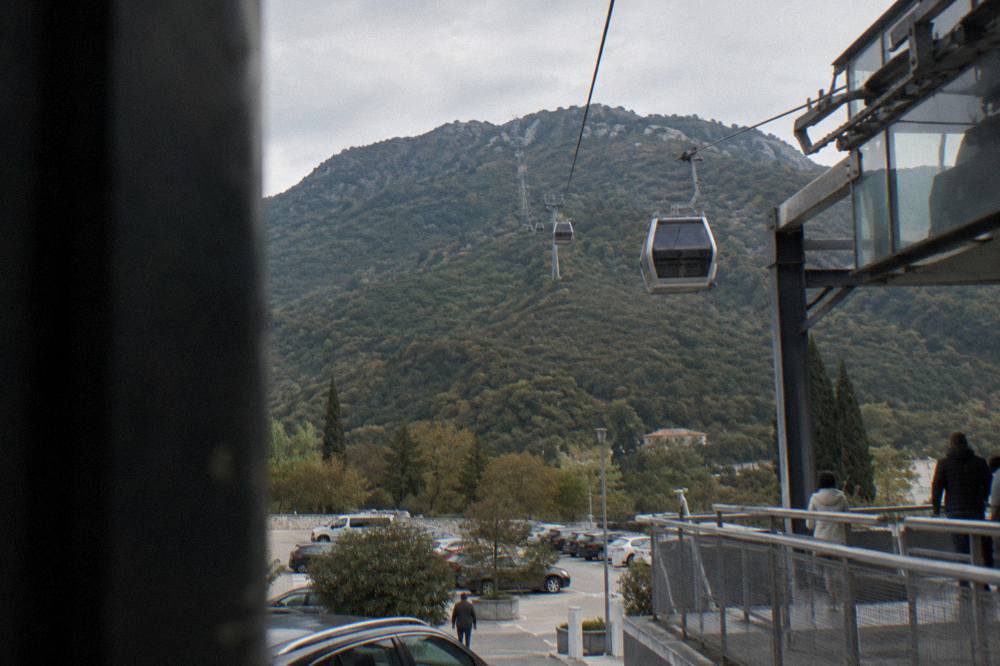 A cable car cabin rising over green slopes toward the top of Mount Dajti above Tirana