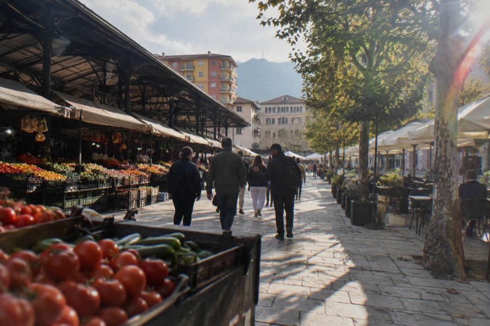 A small group walking with a guide along a market arcade past produce stalls