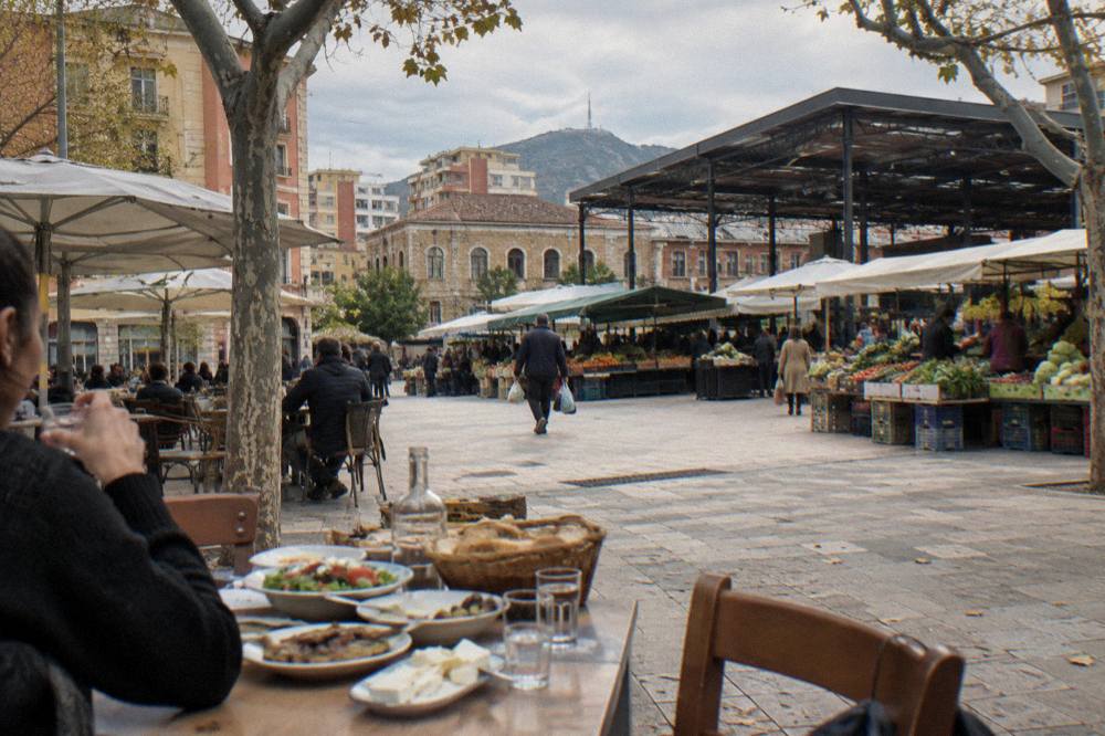 A table set with shared plates of food, bread and small glasses of raki
