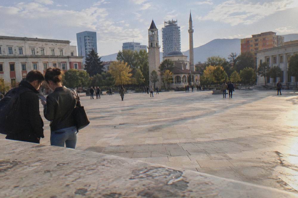 Two people consulting a phone map at the edge of a large pedestrian square